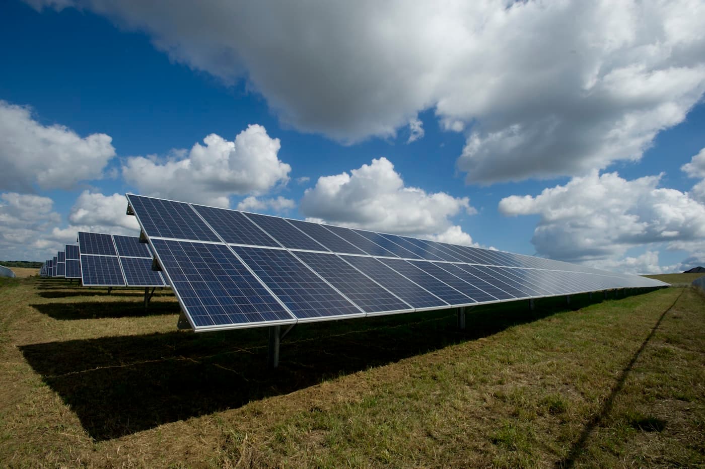 Rows of solar panels in a field under a bright sky